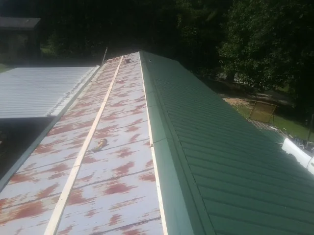 Old rusted panels beside newly installed green metal roofing — Wind Damage Roof Repair by Roofing Brothers in Macomb