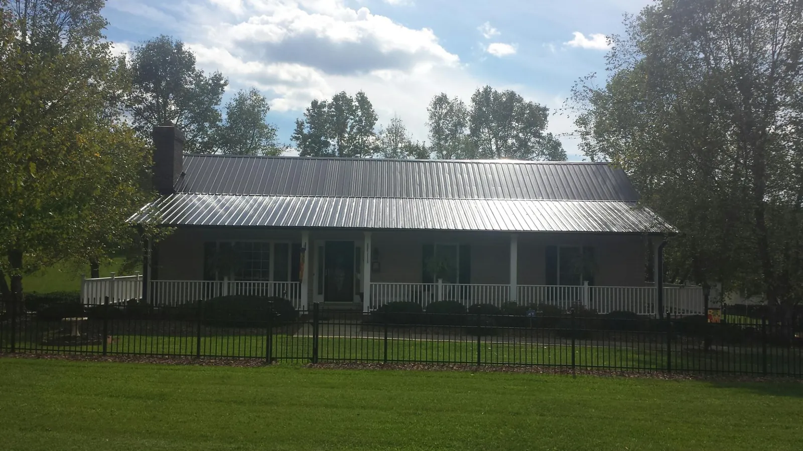 Gray metal roof on a brick ranch with a full width front porch — Gutter Guard Installation work by our crew in Macomb