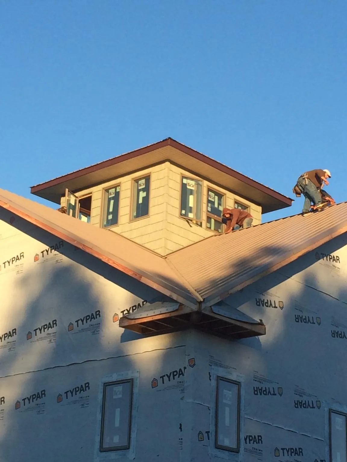 Roofers working around a rooftop cupola on a new metal roof at sunset — Roof Waterproofing in Macomb by Roofing Brothers